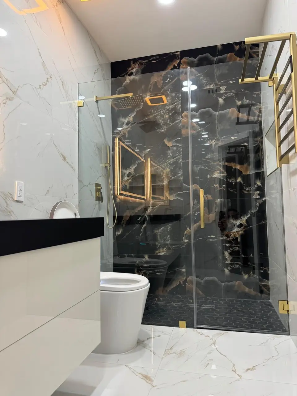 Shower in black and gold marble-look tile with brass hardware